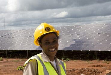 image d'une jeune technicien devant un champs de panneaux solaire pour la transition énergétique au Sahel